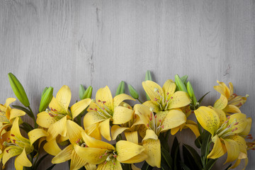  Beautiful yellow lilies on a wooden background.