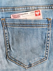 Fragment of Polish Identity Card in back  pocket of jeans. ID card with Coat of arms of Poland (crowned eagle on a red background). Translation of description: Republic of Poland, Identity Card.