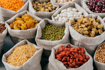 Food concept. Close up cropped shot of various kinds of natural cereals and dried fruit in sacks. Legumes in bags. Products for vegans