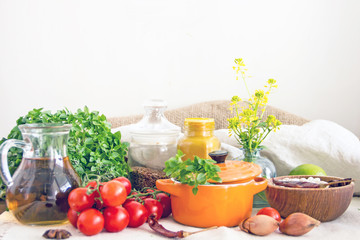 Ingredients and utensils to prepare the food. Fresh basil, cherry tomatoes, beans, olive oil, lime, onion, spices, saucepan, jars in cereals. Culinary background. Copy space