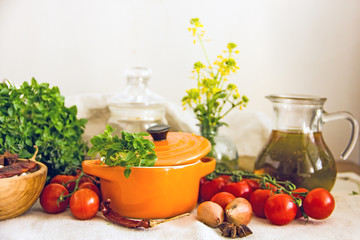 Food and utensils to prepare food. Fresh basil, cherry tomatoes, beans, olive oil, lime, onion, spices, saucepan, jars in cereals. Culinary background. Copy space