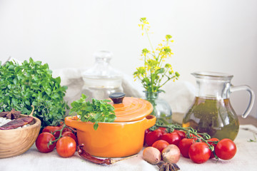Food and utensils to prepare food. Fresh basil, cherry tomatoes, beans, olive oil, lime, onion, spices, saucepan, jars in cereals. Culinary background. Copy space