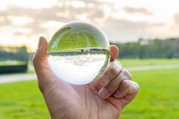 A hand holding a crystal ball for optical illusion. Known as an orbuculum, is a crystal or glass ball and common fortune telling object. Performance of clairvoyance and scrying