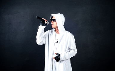 Karaoke man sings a song into a microphone, on a dark concrete background. A funny man holds a microphone in his hand at a karaoke singer singing a song! Pivets against dark background