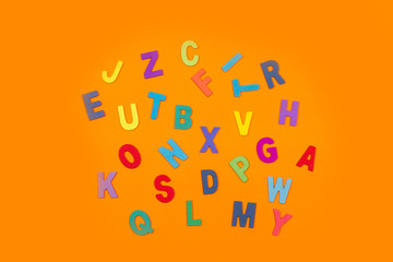 Letras de abecedario de colores sobre un fondo naranja liso y aislado. Vista superior