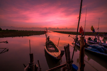 The background of the morning sunrise scenery by the sea, the fishing boats parked in the blurred beauty of the sea breeze that passes through, is the beauty of nature during traveling.