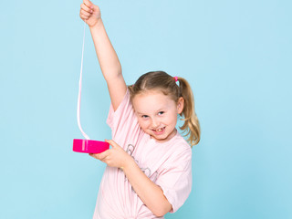 beautiful 8 year old girl is playing with pink slime in front of blue background