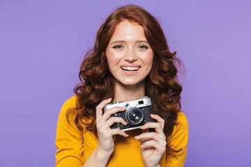 Photo of european redhead woman wearing yellow clothes holding retro vintage camera and taking picture