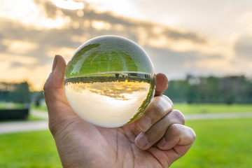 A hand holding a crystal ball for optical illusion. Known as an orbuculum, is a crystal or glass ball and common fortune telling object. Performance of clairvoyance and scrying