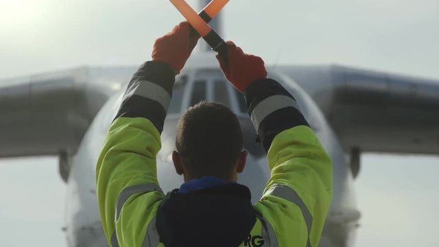 Traffic controller in uniform regulating the movement of a big jet in airport  