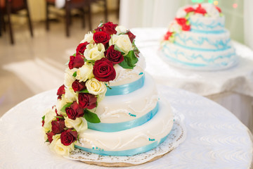 wedding cake decorated with red and white flowers roses on white background