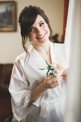Gorgeous bride in robe posing and preparing for the wedding ceremony face in a room