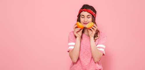 Portrait of a girl with oranges in hand, on a pink background