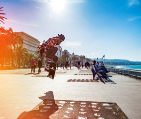 Silhouette of skateboarder jumping in the city of Nice on background of promenade near the sea