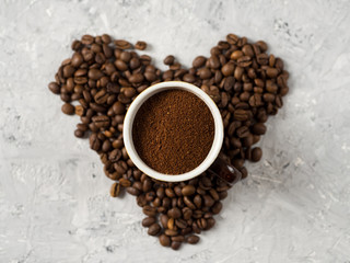 A Cup of freshly ground coffee on the table with coffee beans in the shape of a heart