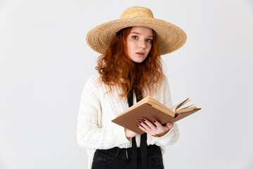 Beautiful young cute girl redhead posing isolated over white wall background holding book reading.