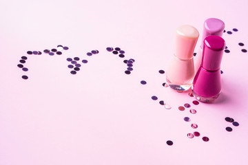 Pink nail polishes with confetti heart. Copy space.
