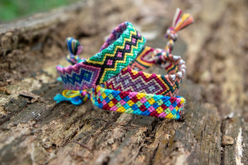 Group of colorful handmade homemade natural woven bracelets of friendship on old wood background, checkered patterns