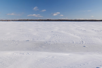 Fototapeta na wymiar Surface of the frozen river. Snow dunes formed after a night blizzard. Winter in Arkhangelsk region. Russia