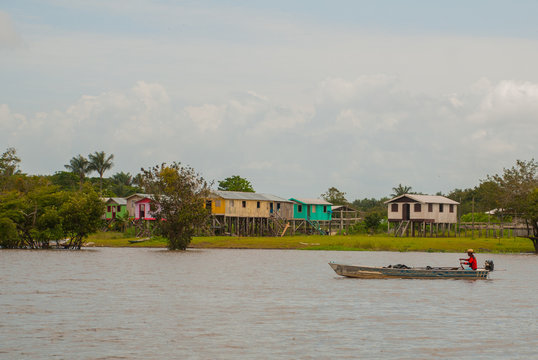 Amazon river, Amazonas, Brazil: Fisherman dancing on the boat. Wooden local huts, houses on the Amazon river in Brazil.