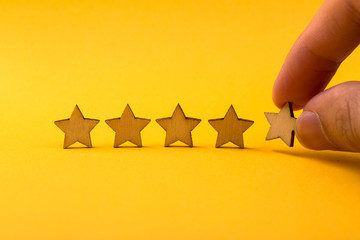 Hand putting wooden five star shape on yellow background
