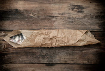 Fresh whole sea bass fish wrapped in a brown paper