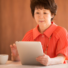 タブレットPCを見るシニア女性