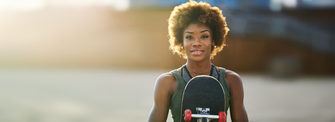 happy african american woman holding skateboard portrait © Joshua Resnick