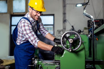 Turner worker is working on a lathe machine in a factory