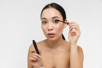 Fototapeta premium Pretty asian woman with healthy skin posing naked isolated over white wall background holding mascara.