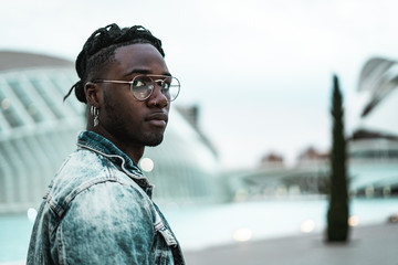 Handsome portrait African American guy walking city street with modern glasses and casual dress.