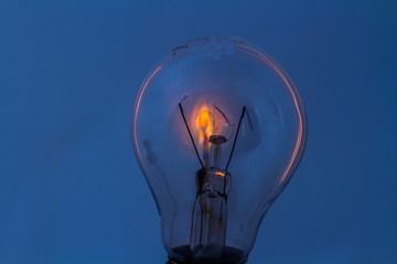 A dead electric light bulb with a burning matchstick behind it isolated on a clear background image with copy space in landscape format
