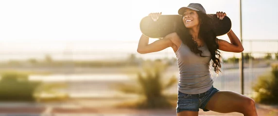 Foto op Plexiglas Smiling woman holding skateboard during sunse in panoramic composition © Joshua Resnick