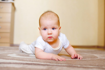 Baby kid 6 months playing on the floor in the room. The child learns to crawl. First steps and crawls.