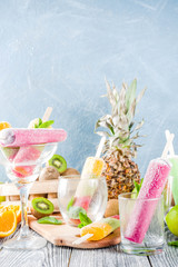 Colorful fruit ice cream popsicle. Juicy gelato lollypops on sticks, with different fresh tropic fruits, wooden background copy space