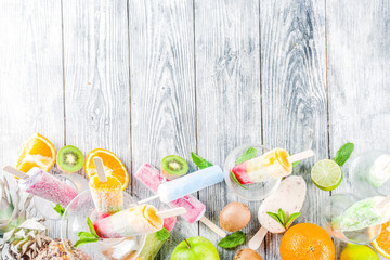Colorful fruit ice cream popsicle. Juicy gelato lollypops on sticks, with different fresh tropic fruits, wooden background copy space