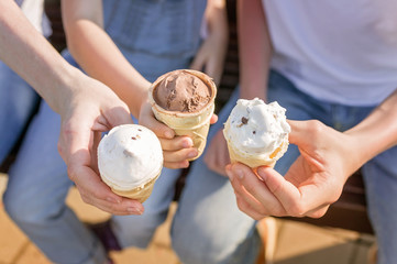 Vanilla and chocolate ice cream in women's and children's hands. Happy family hands