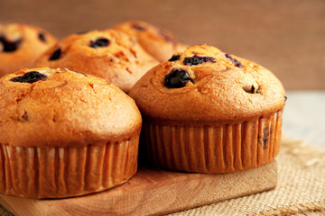 Muffins with berry close-up. Breakfast in the form of muffins with currants or blueberries. Big muffins on a cutting board on burlap. Baking for breakfast.