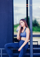 Fototapeta premium Shot of beautiful female runner standing outdoors holding water bottle. 