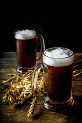 Two Homemade craft beer mugs, dark wooden background copy space