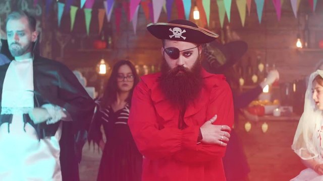 Portrait of a handsome bearded man in pirate costume at a halloween party. Authentic pirate with one eye and jollyroger hat.