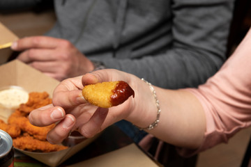 Mano mojando pollo frito en salsa roja de tomate