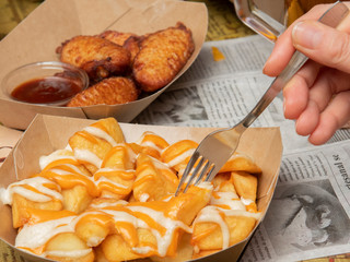 Persona comiendo tapa de patatas con salsa