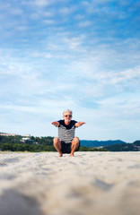 Senior man doing stretching exercises on the beach