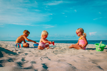 kids -little boy and girls- play with sand on beach