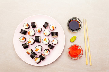 Romantic heart sushi dinner. Maki rolls with ginger, wasabi and soy sauce on rosy plate. Concept for Valentine's Day or March 8th. Stone background, top view