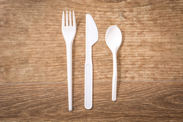 Disposable plastic cutlery on wooden table. Top view