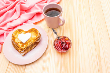Obraz na płótnie Canvas Heart shaped pancakes for romantic breakfast with strawberry jam and black tea. Shrovetide (carnival) concept. On wooden background