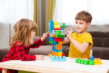 Little boy playing with lots of colorful plastic blocks constructor and builds the robot indoor. 