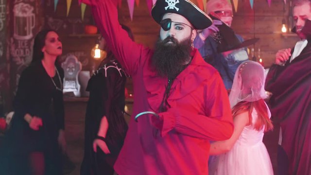 Evil pirate costume with an axe and a hook dancing at a halloween party. Pirate with long black beard having fun at a party.